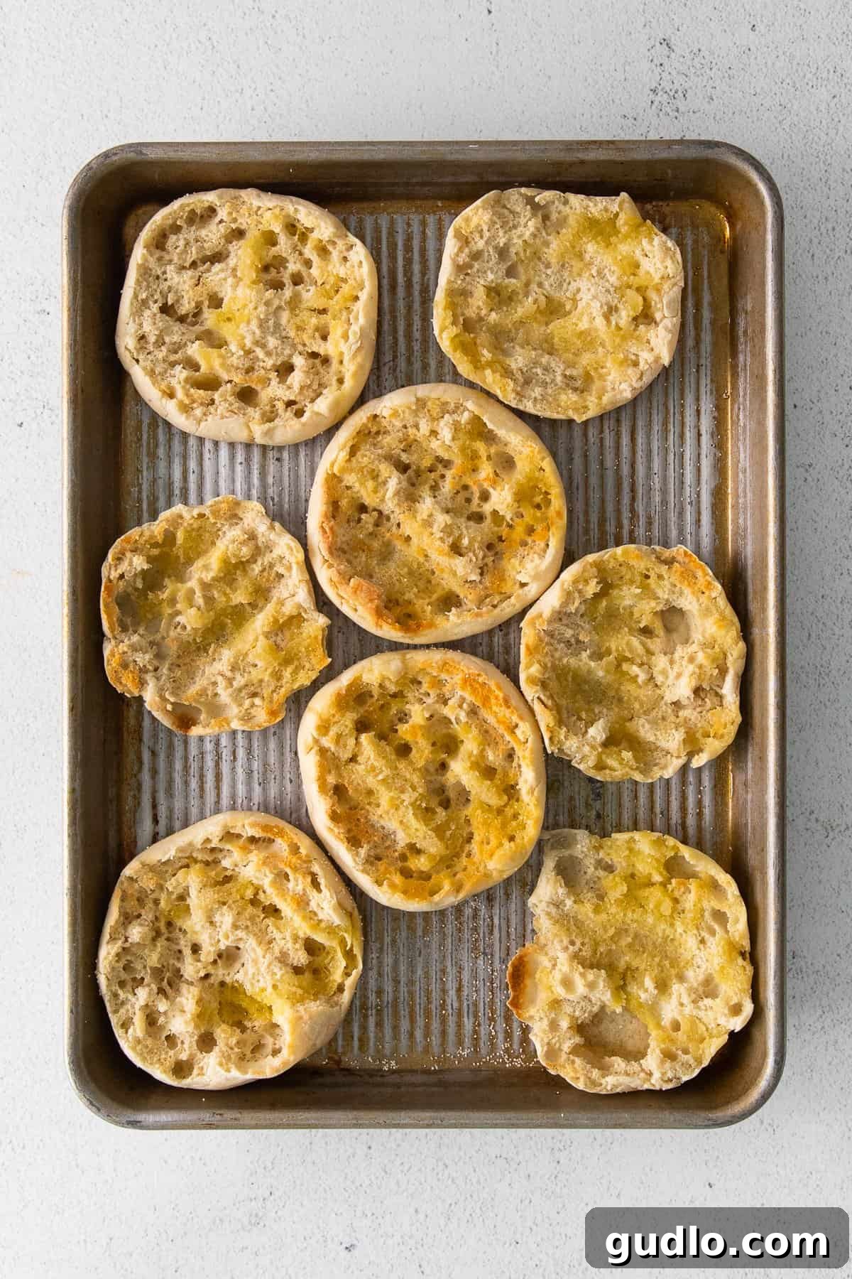 English Muffin Pizzas -- an easy 30-minute meal that the whole family will love. Top your English muffins with marinara sauce, cheese, and your favorite toppings! Toasted English muffin halves arranged on a baking sheet, ready for toppings.