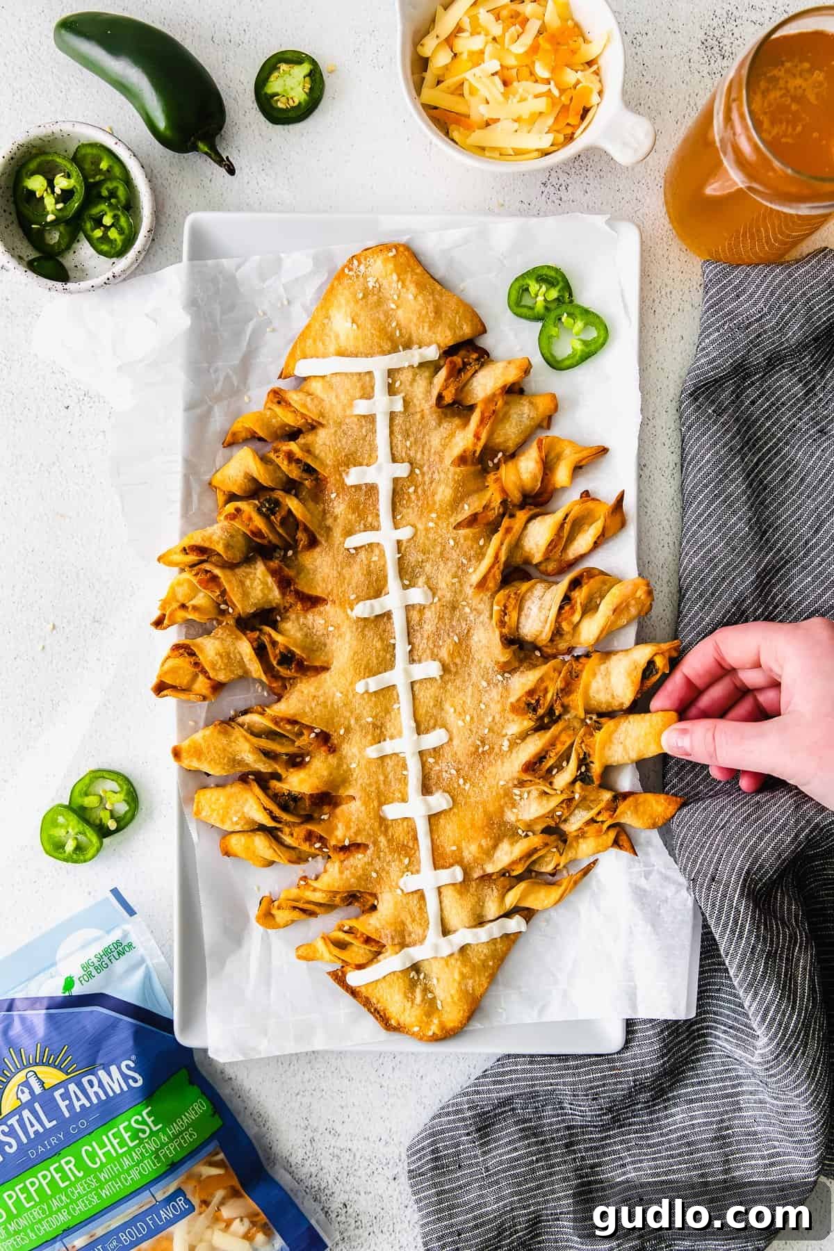 It's game day and we're making these jalapeño popper football-shaped stuffed cheesy breadsticks! This appetizer is a deliciously perfect dish to pass. football-shaped cheesy breadsticks with a hand pulling off one breadstick