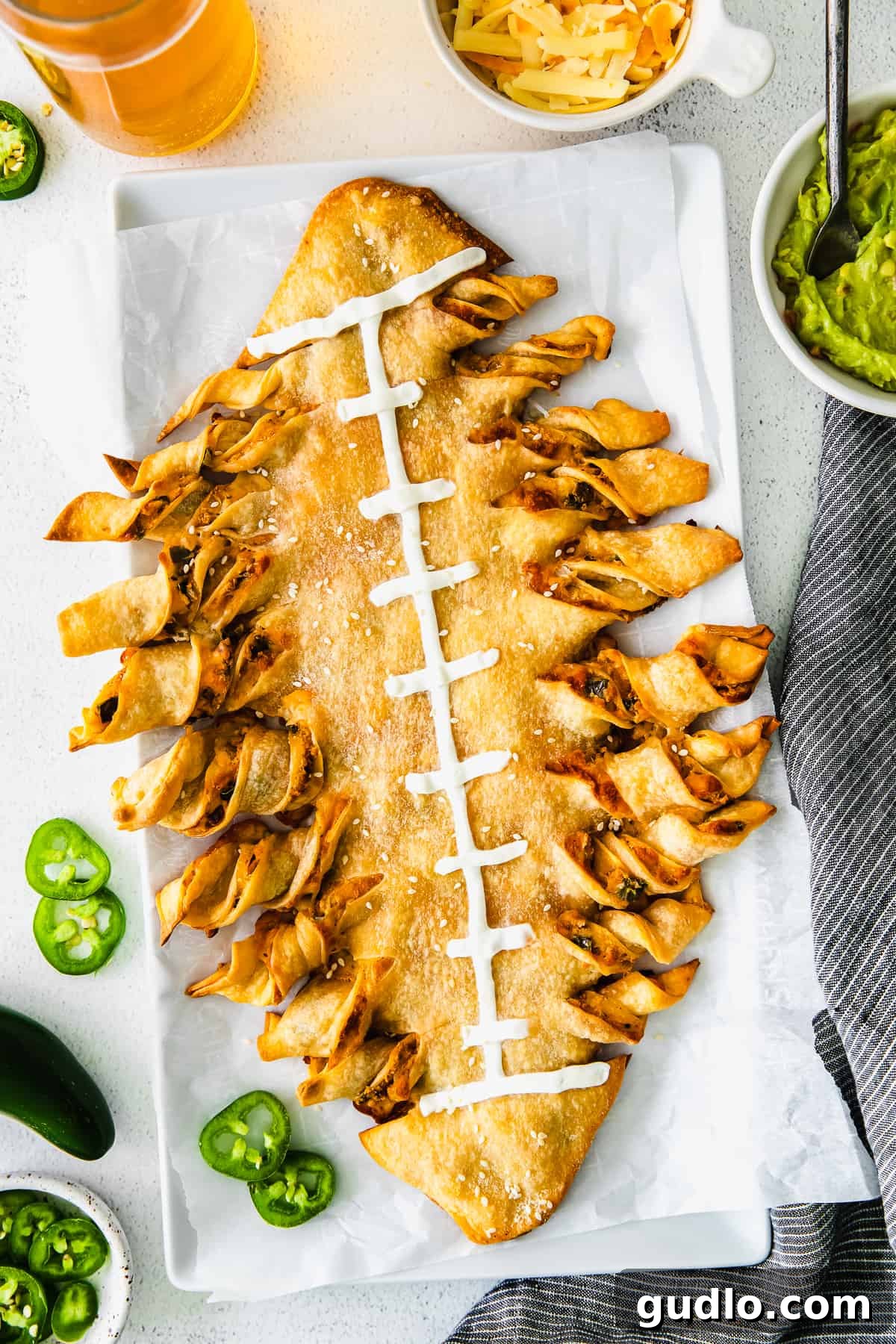 It's game day and we're making these jalapeño popper football-shaped stuffed cheesy breadsticks! This appetizer is a deliciously perfect dish to pass. football cheesy breadsticks topped with sour cream ready to be served