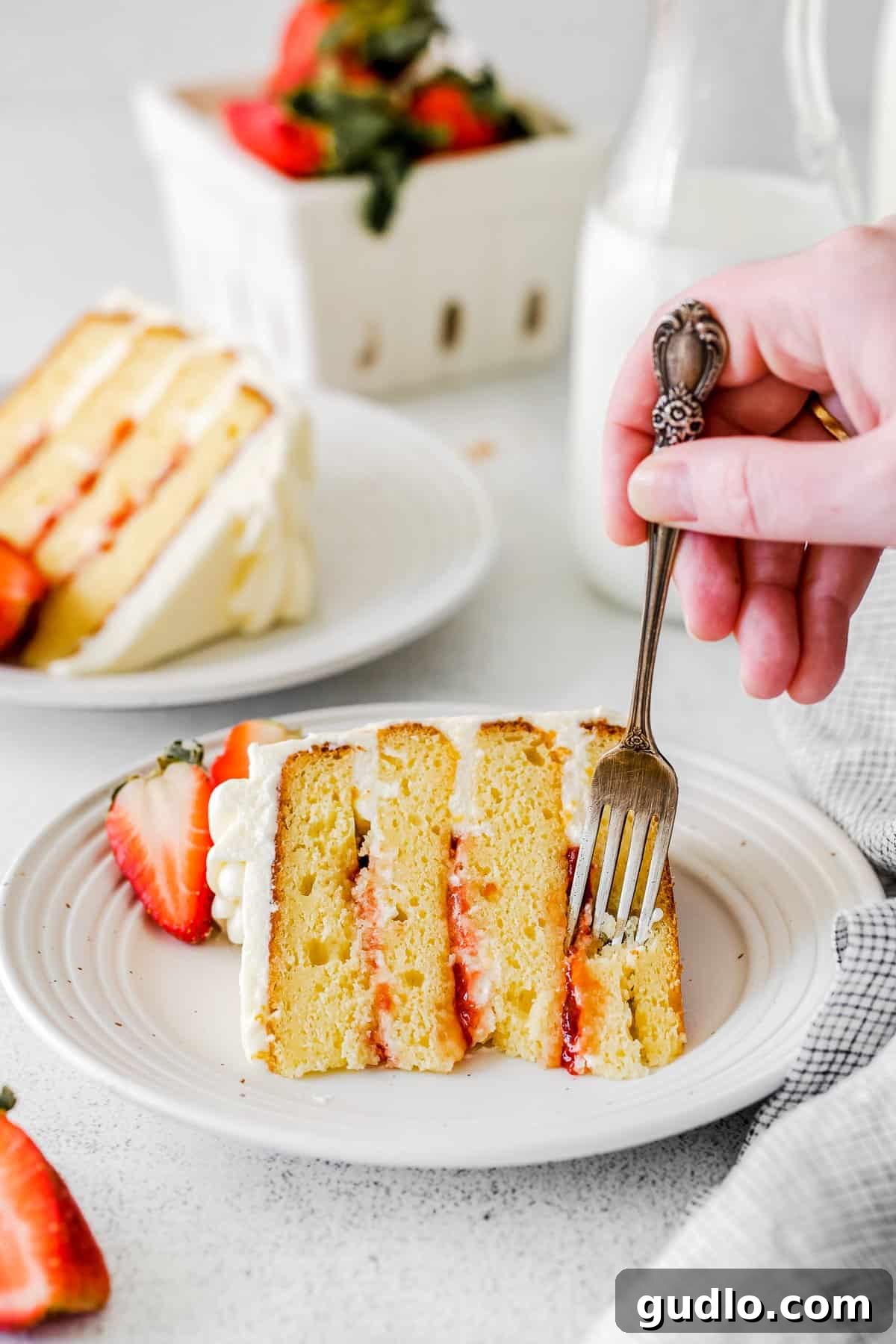 Dreamy Strawberry Ricotta Layer Cake 2 A beautifully decorated strawberry ricotta layer cake, garnished with fresh strawberries and lemon slices on a white cake stand, ready to be served.
