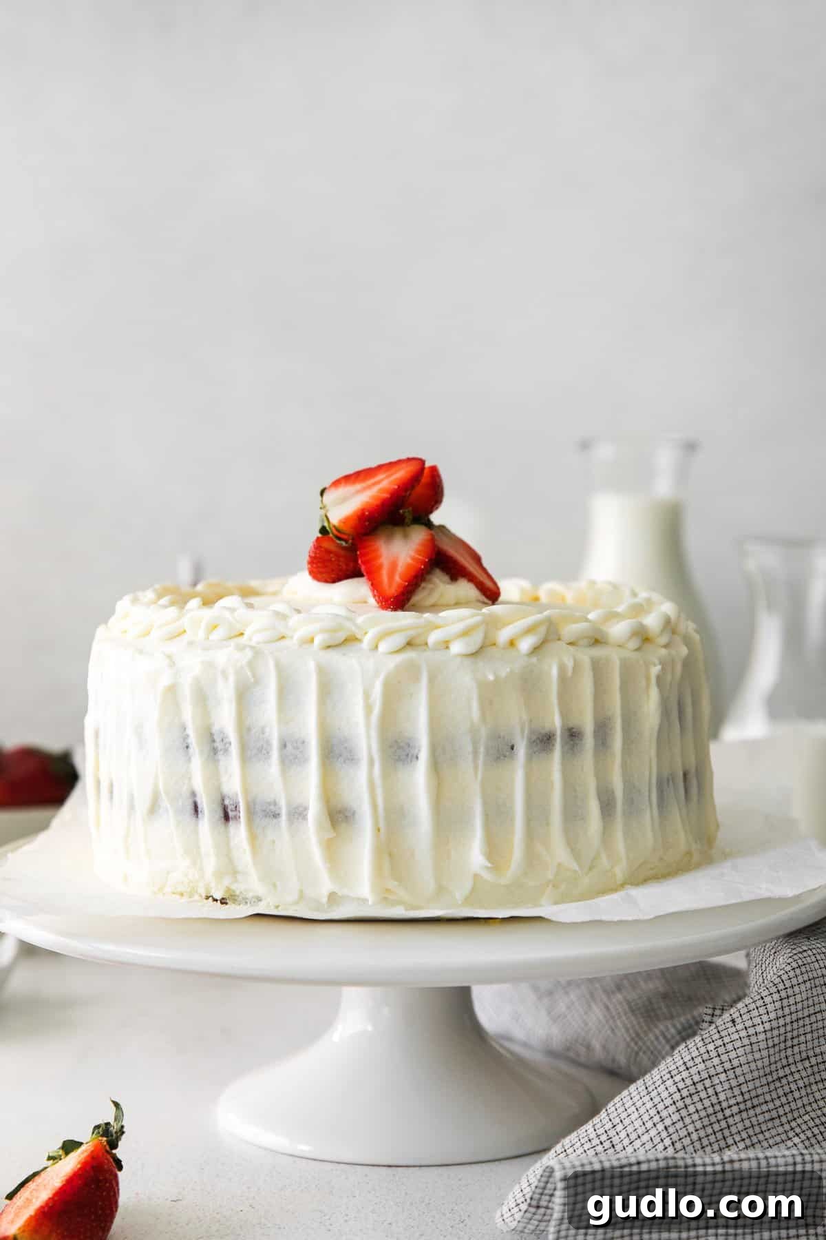 Dreamy Strawberry Ricotta Layer Cake 11 A beautifully decorated strawberry ricotta layer cake, adorned with fresh strawberry slices and intricate frosting swirls on top.
