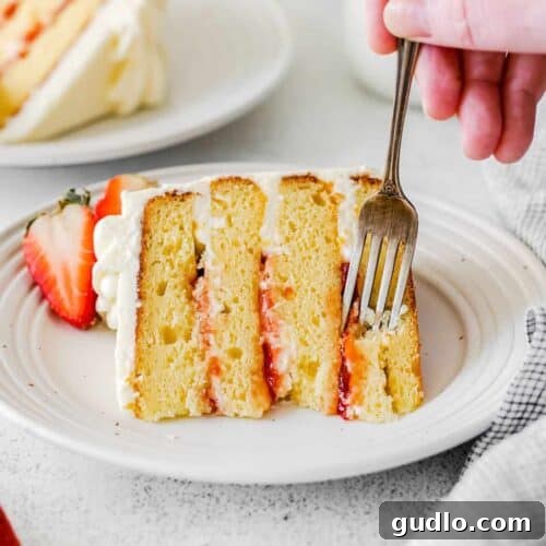 Dreamy Strawberry Ricotta Layer Cake 14 A slice of elegant Lemon Ricotta Cake on a pristine white plate, accompanied by fresh berries and a sprig of mint, ready to be savored.