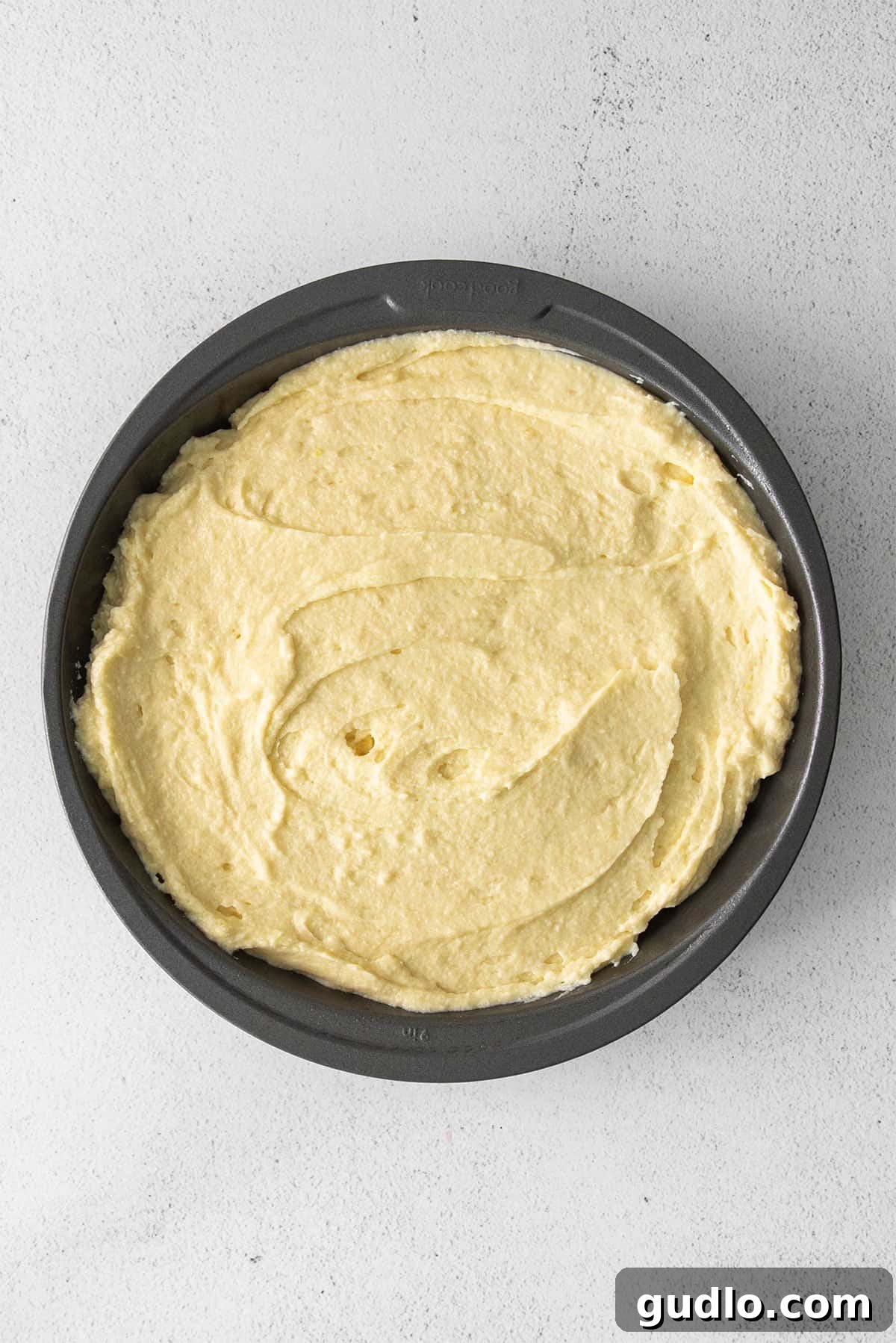Dreamy Strawberry Ricotta Layer Cake 6 Smooth, evenly spread ricotta cake batter in a round cake pan lined with parchment paper, ready for baking.