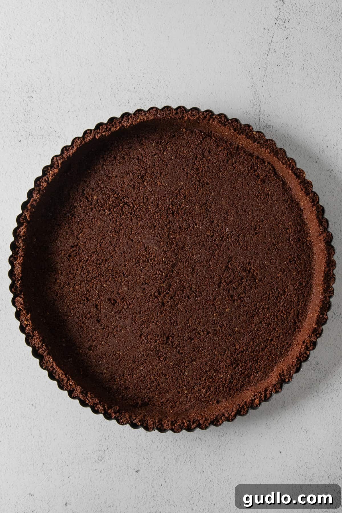 A freshly pressed chocolate graham cracker crust, ready for filling.