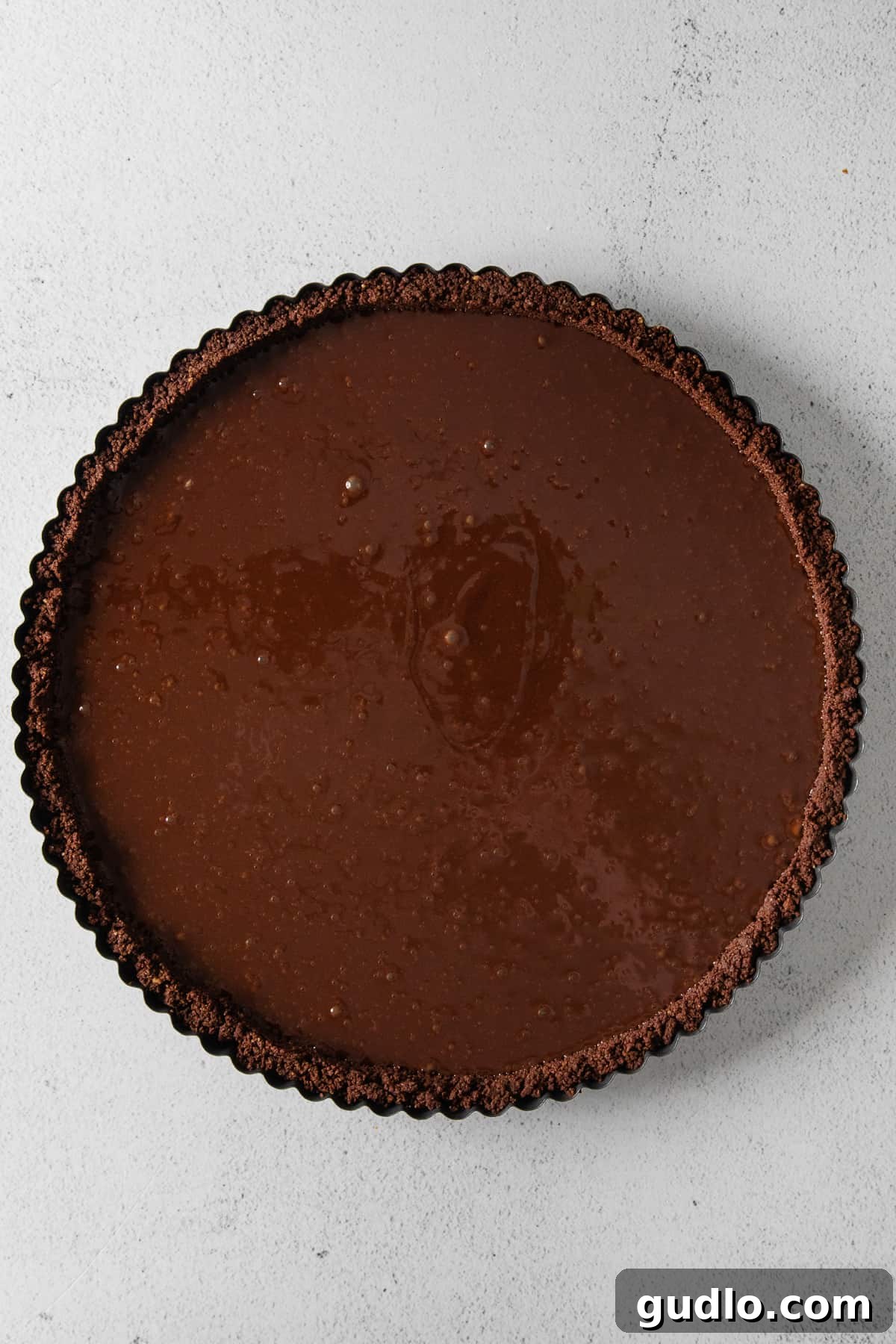 A chocolate tart, unbaked, showcasing the smooth chocolate filling within the prepared crust.