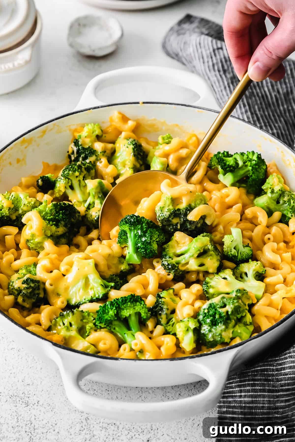 Creamy Broccoli Mac and Cheese with Spoon A generous serving of creamy broccoli mac and cheese on a spoon, showcasing tender macaroni, bright green broccoli florets, and gooey melted cheddar cheese.