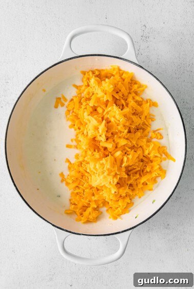Cheesy sauce blending with rice in a pan on a white background, demonstrating the smooth texture.
