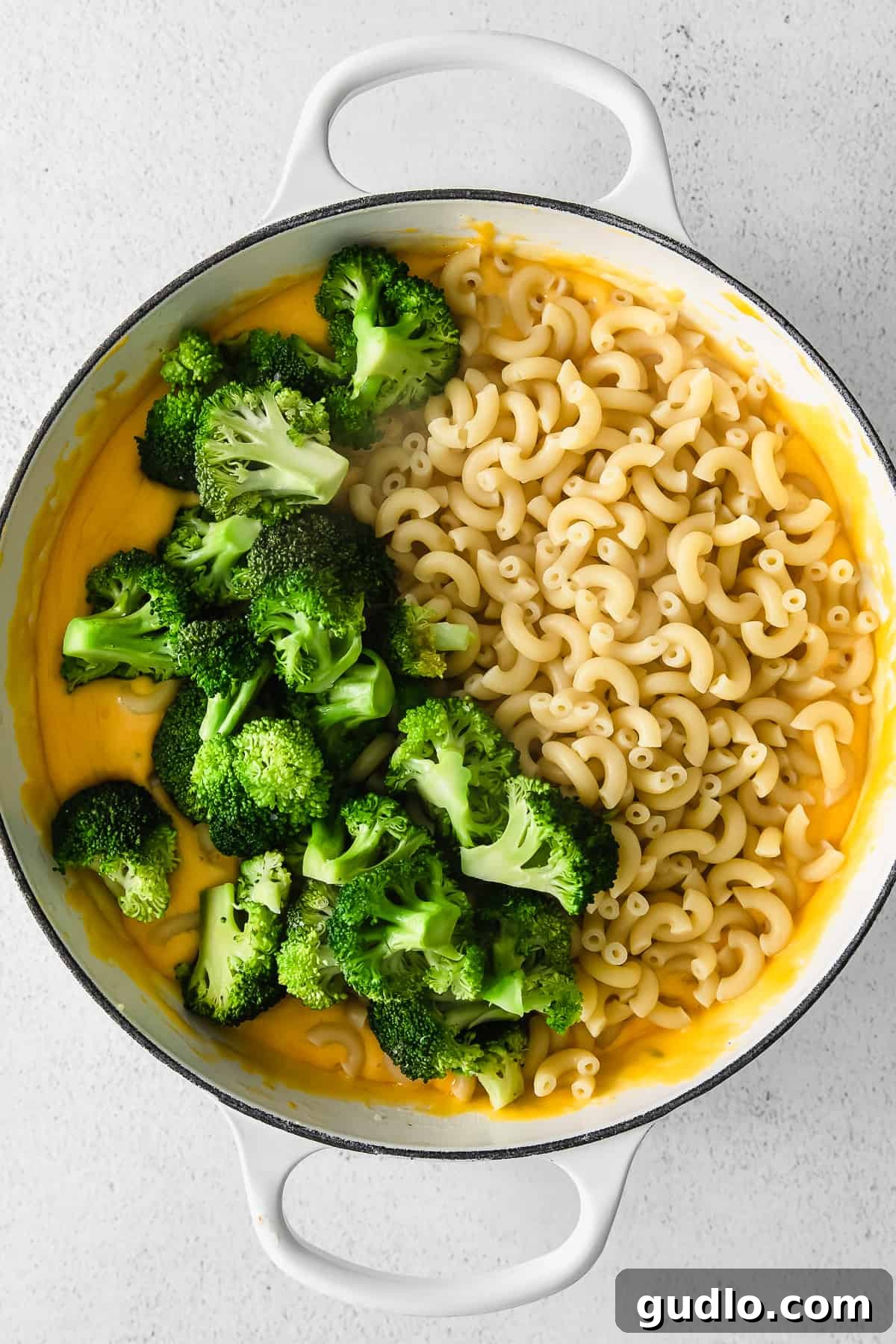 Tossing Broccoli Mac and Cheese A vibrant close-up of macaroni, cheese sauce, and bright green broccoli florets mixing together in a large pot, ready to be served.