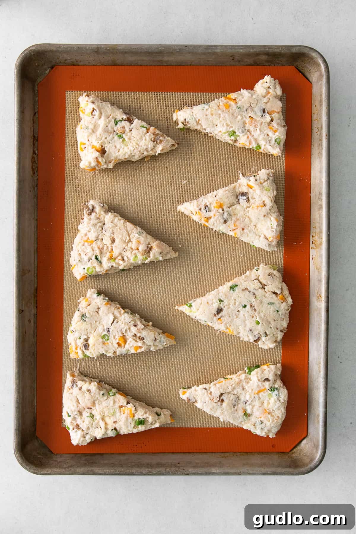Scone Dough Wedges on Baking Sheet Raw scone wedges, perfectly cut and arranged on a parchment-lined baking sheet, awaiting their crucial chilling period in the freezer.