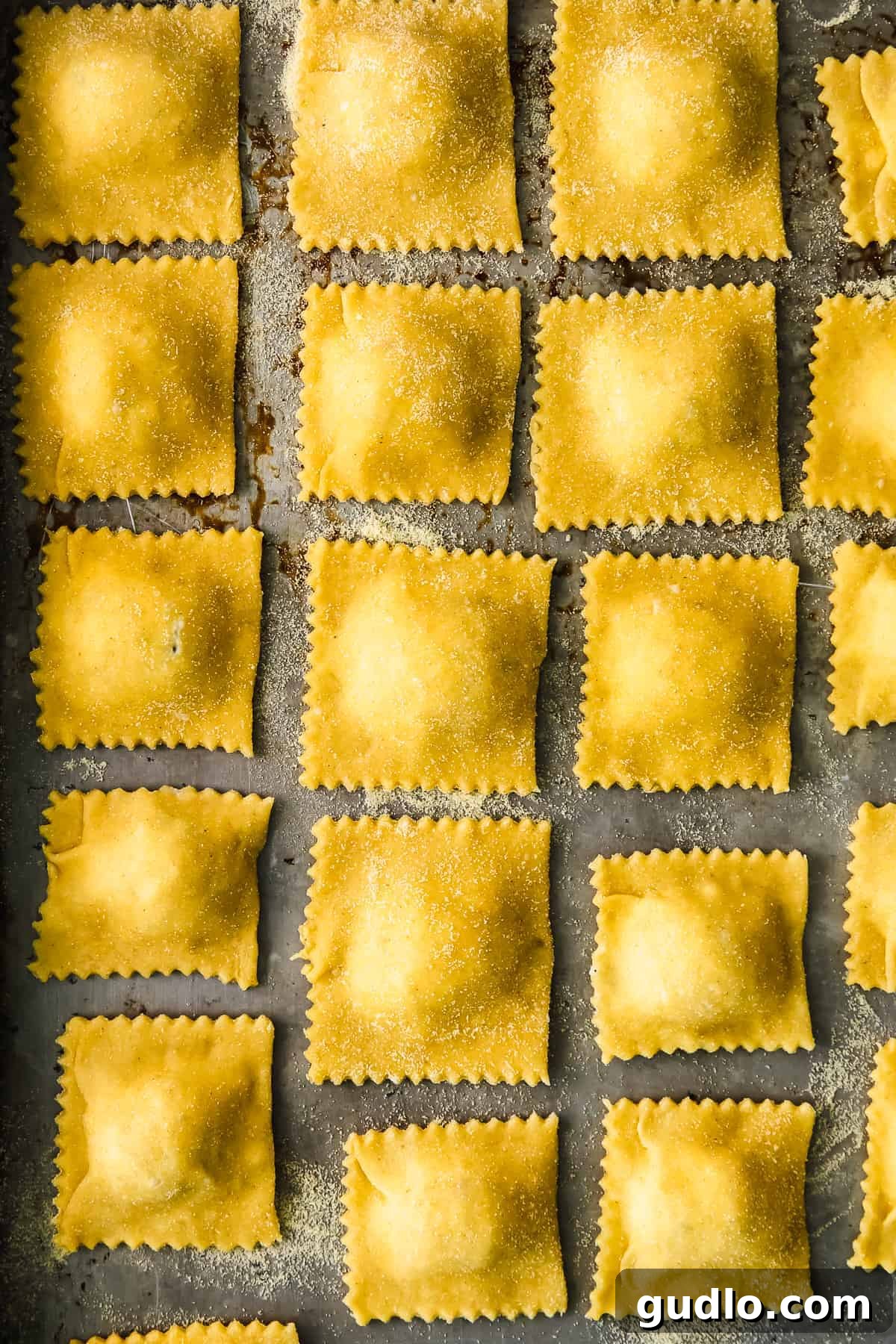 Homemade ravioli on a baking sheet, ready to be cooked.