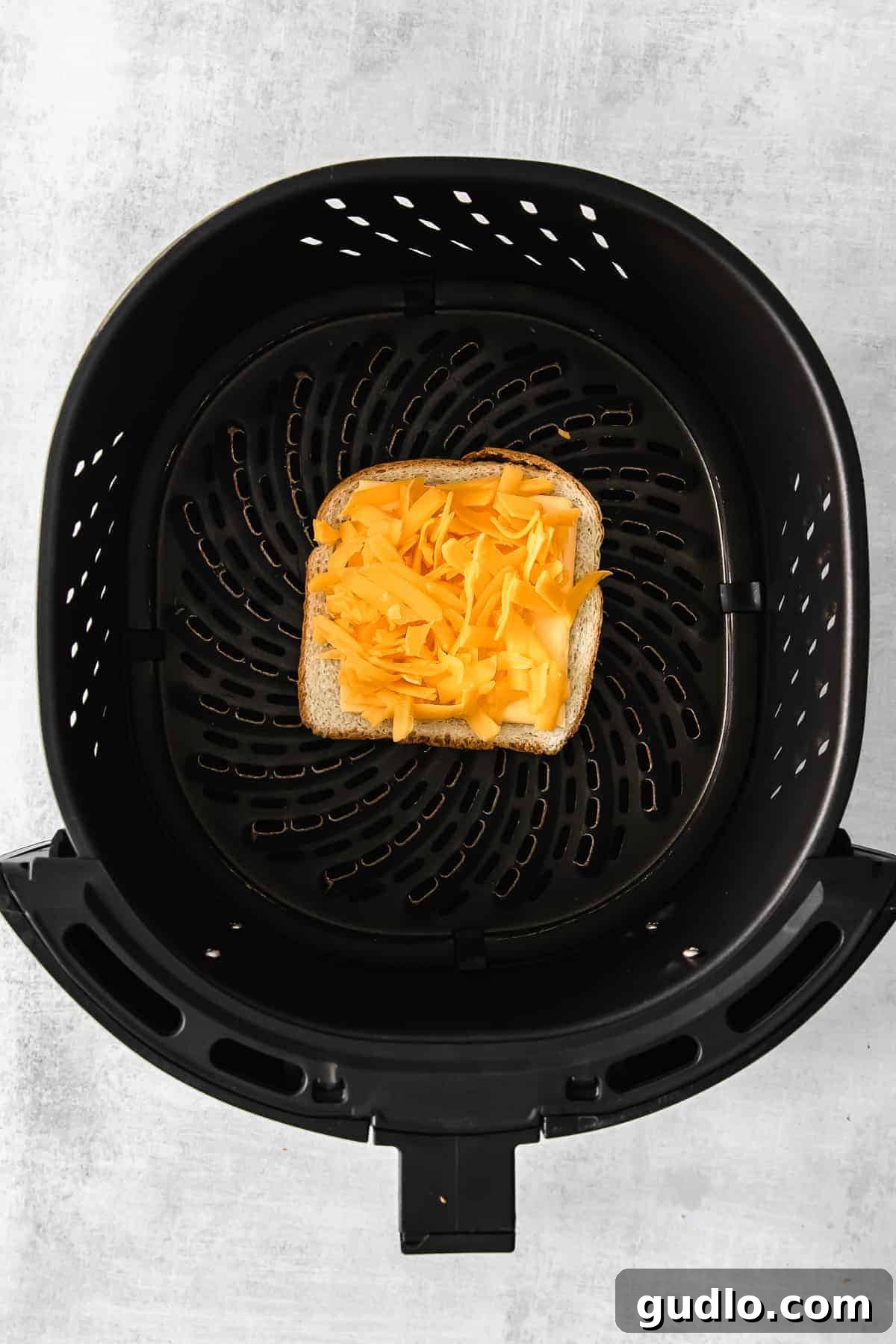 Perfectly crispy on the outside and cheesy on the inside air fryer grilled cheese! Learn how to make grilled cheese in air fryer in less than 15 minutes. A perfectly golden-brown grilled cheese sandwich cooking in an air fryer basket.
