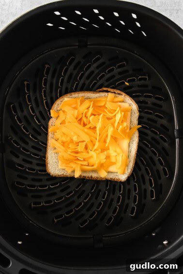 Golden Crispy Air Fryer Grilled Cheese 4 Bread and cheese being layered in an air fryer basket.