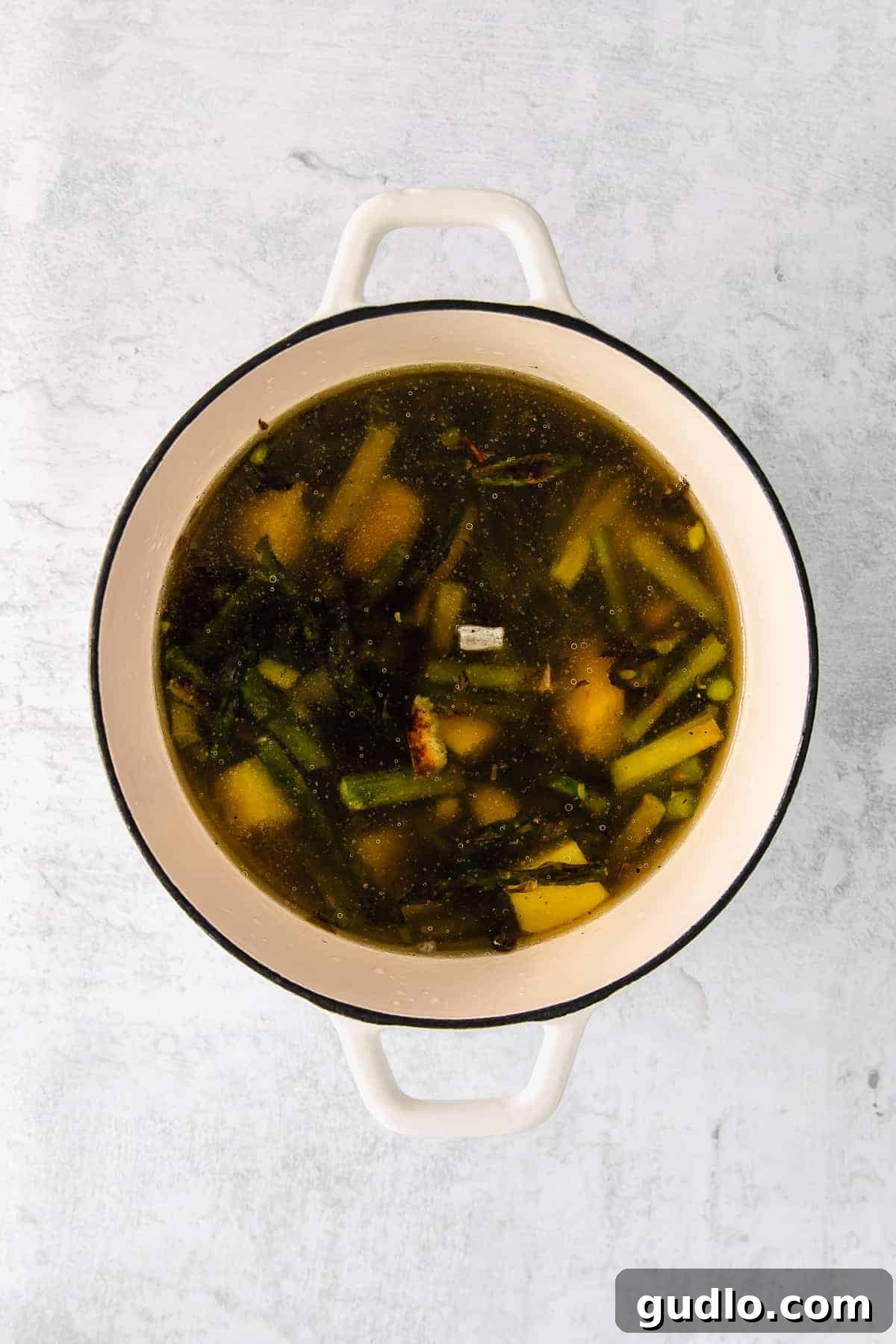 Roasted vegetables and chicken broth simmering in a Dutch oven.