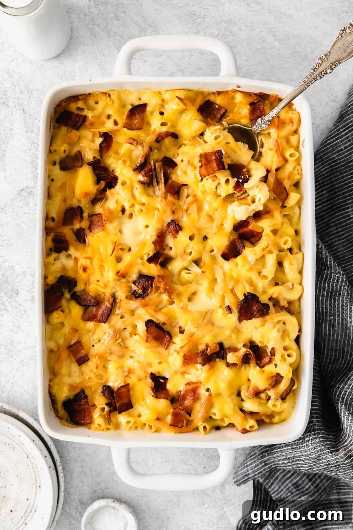 Golden-brown baked bacon mac and cheese in a white casserole dish, ready to be served.