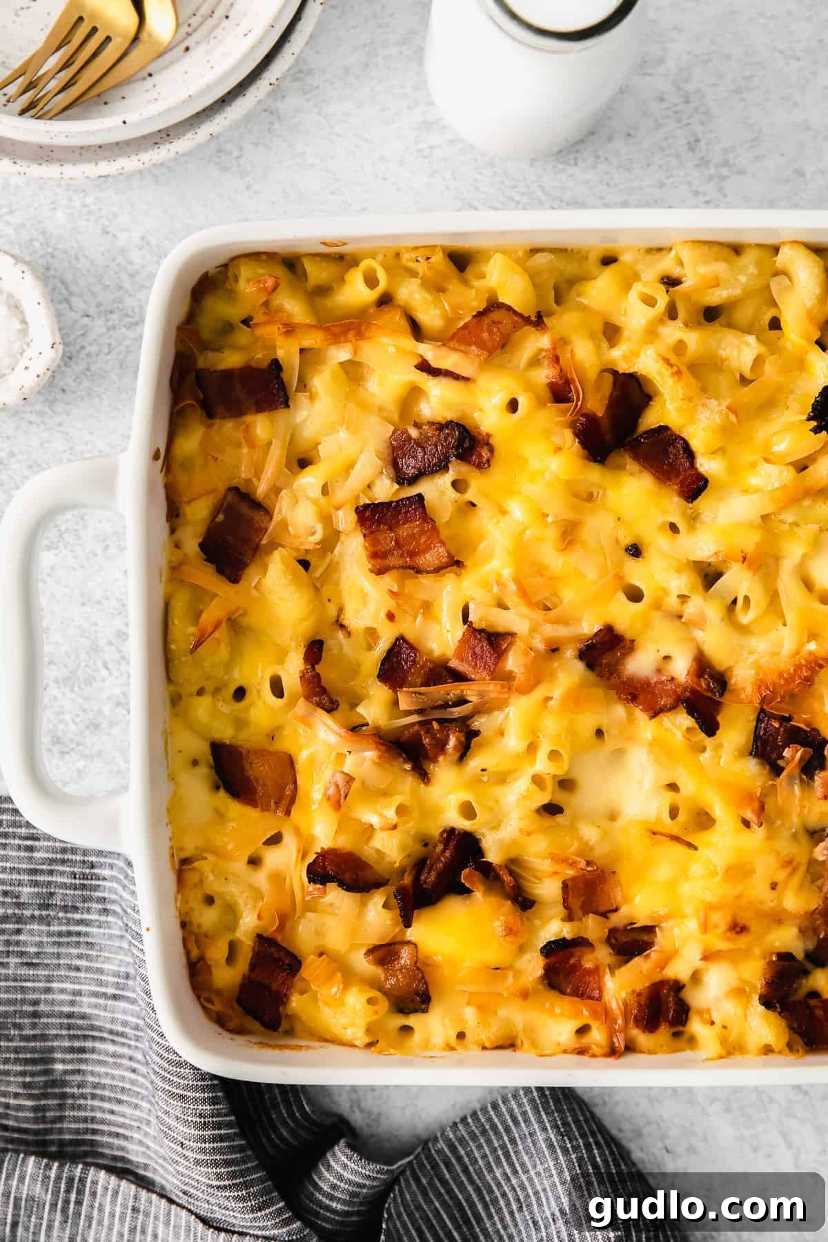 A generous serving of bacon mac and cheese in a casserole dish, garnished with fresh herbs, ready for a family meal.