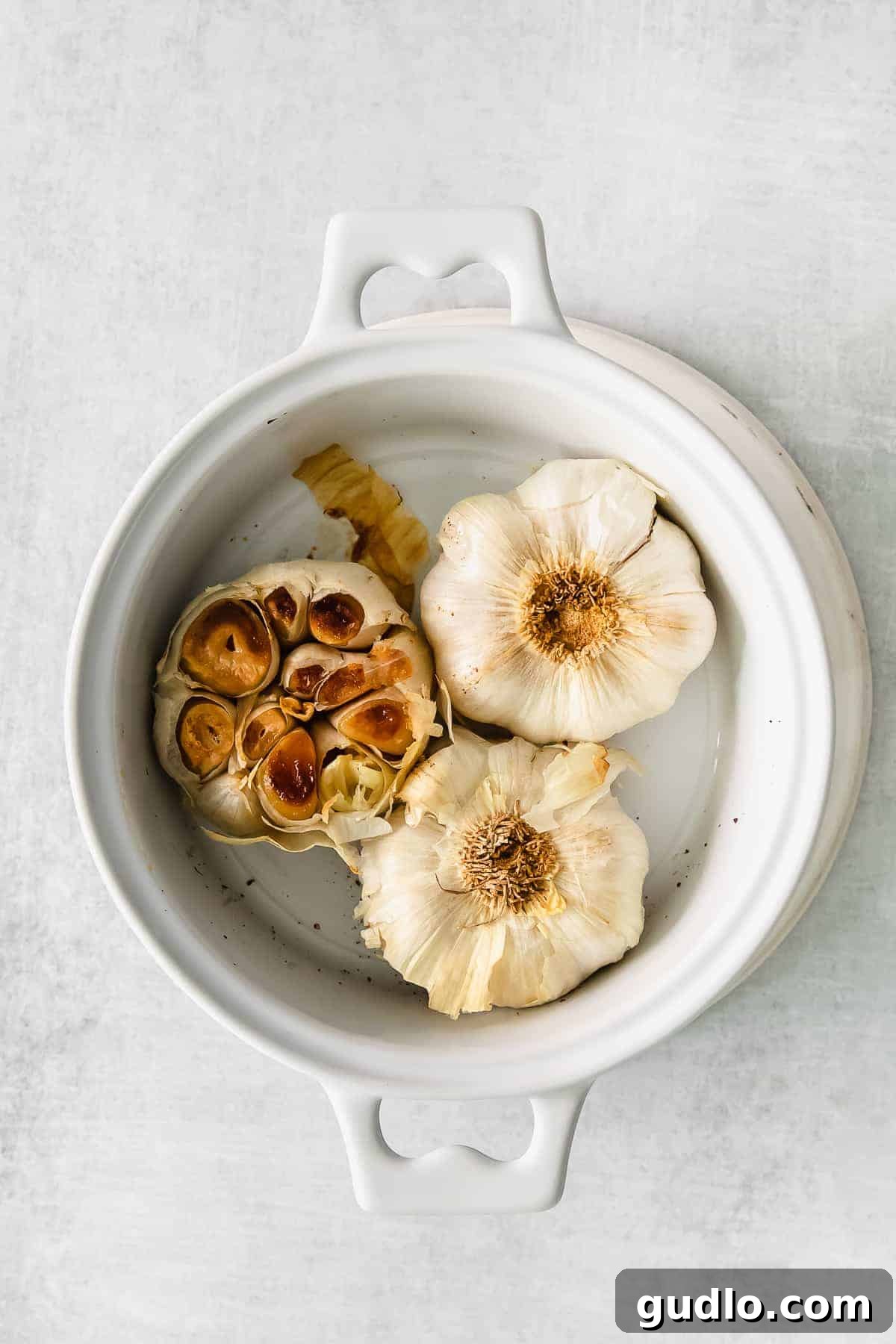 Roasted Garlic for Texas Toast Perfectly roasted garlic bulbs in a small white bowl, ready to be mashed into a flavorful paste.
