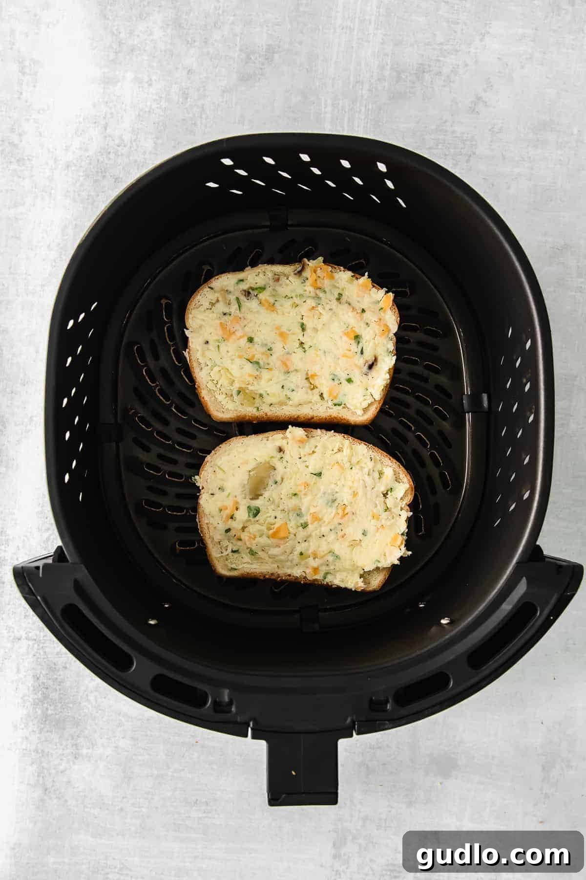 Air Frying Texas Toast Two slices of golden-brown air-fried Texas toast, perfectly crisp with melted cheese, inside an air fryer basket.