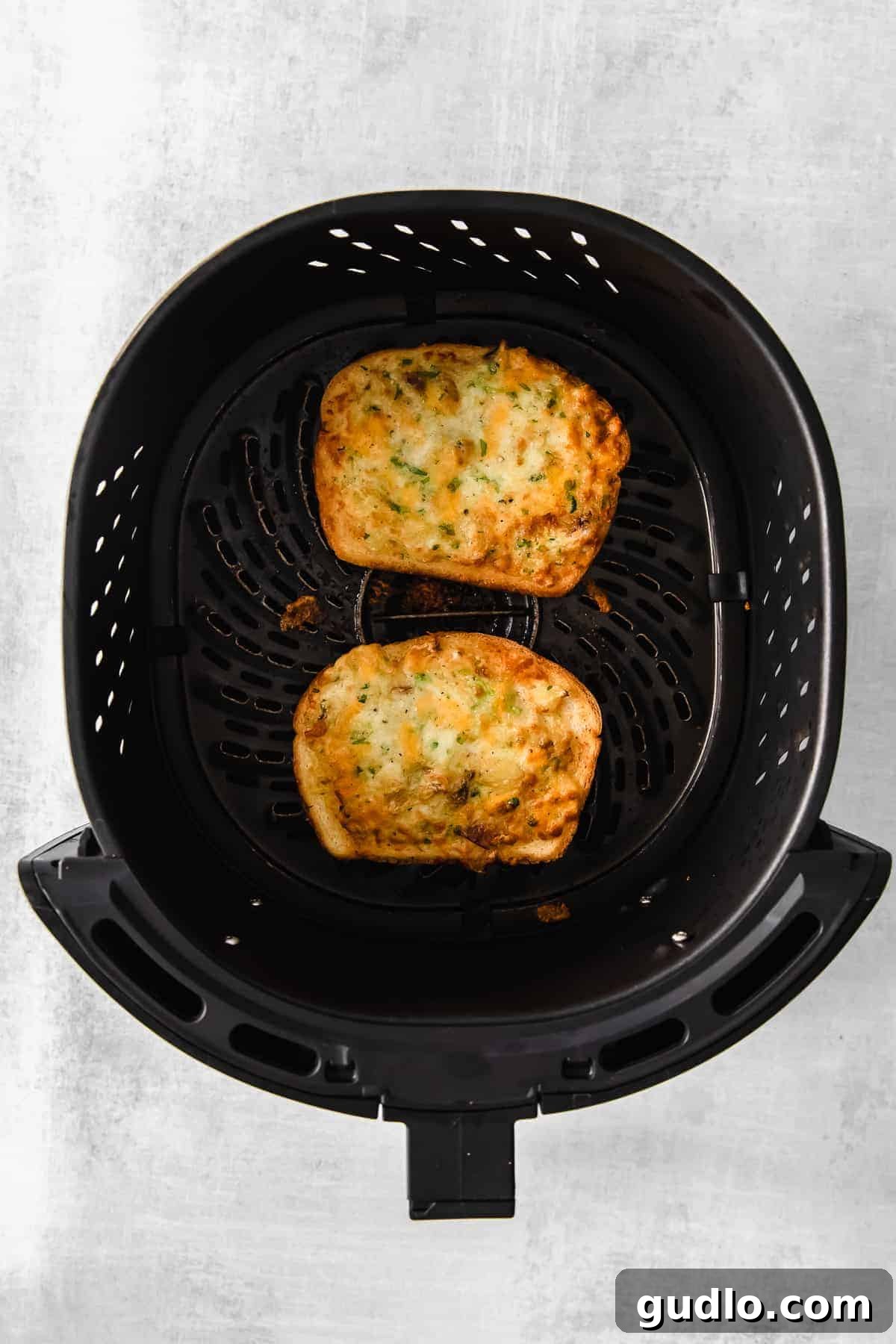Freshly Cooked Air Fryer Texas Toast Perfectly air-fried Texas toast slices with melted cheese, served in an air fryer basket, ready to eat.