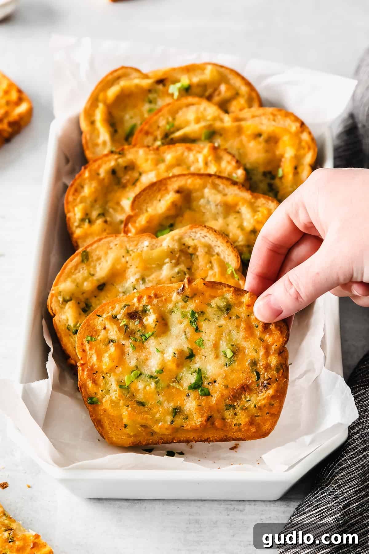 Delicious Air Fryer Texas Toast Stack Stacked slices of air fryer Texas toast in a serving tray, garnished with green herbs.