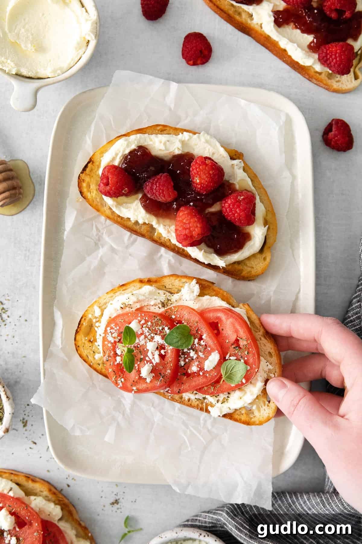 Two slices of golden-brown mascarpone toast, one sweet with berries and the other savory with tomatoes, artfully arranged on a ceramic plate, ready to be enjoyed.
