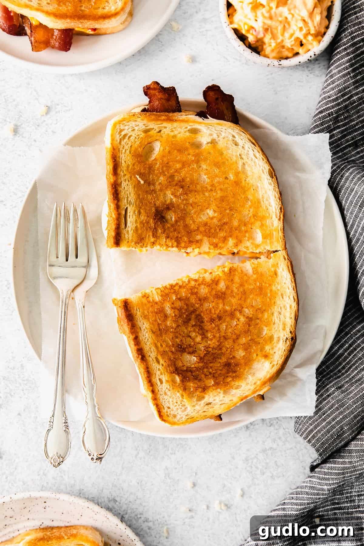 A perfectly cooked fancy grilled cheese, sliced in half and served on a white plate, ready to be devoured.