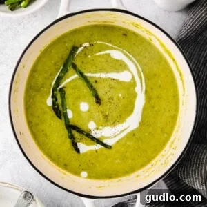 Parmesan-Crusted Asparagus 2 A vibrant bowl of creamy asparagus soup garnished with fresh asparagus tips and a swirl of sour cream.