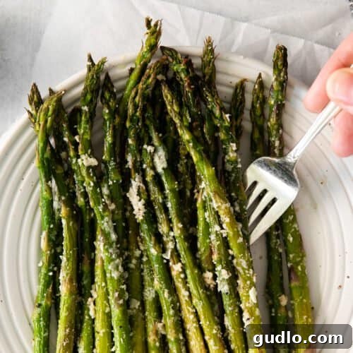 Parmesan-Crusted Asparagus 3 A top-down view of roasted parmesan asparagus in a square dish, sprinkled with cheese.