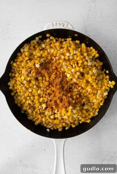 Corn browning in a skillet on a white background.