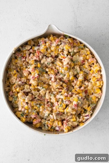 Corn salad in a white bowl being mixed.