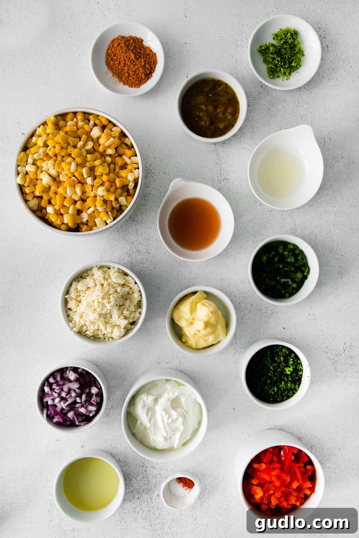 A collection of fresh ingredients for Mexican corn salad, neatly arranged in small bowls, ready for preparation.