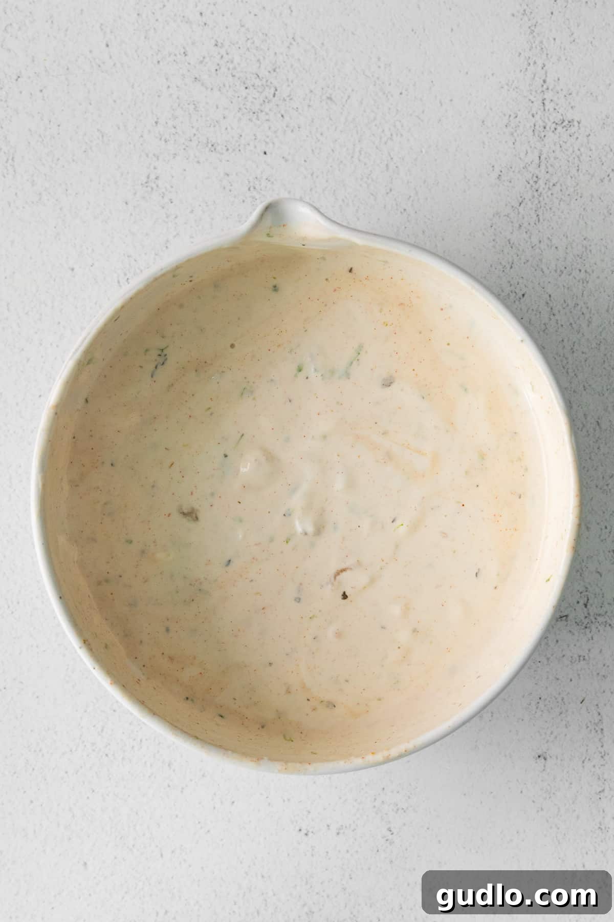 A smooth, creamy queso fresco sauce in a white bowl, ready to be added to the corn salad.