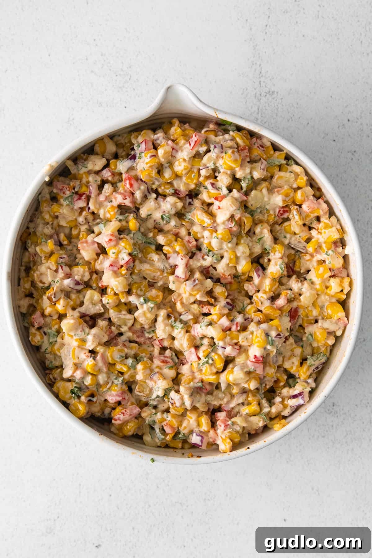 A close-up of the finished Mexican corn salad in a rustic white bowl, garnished with fresh cilantro.