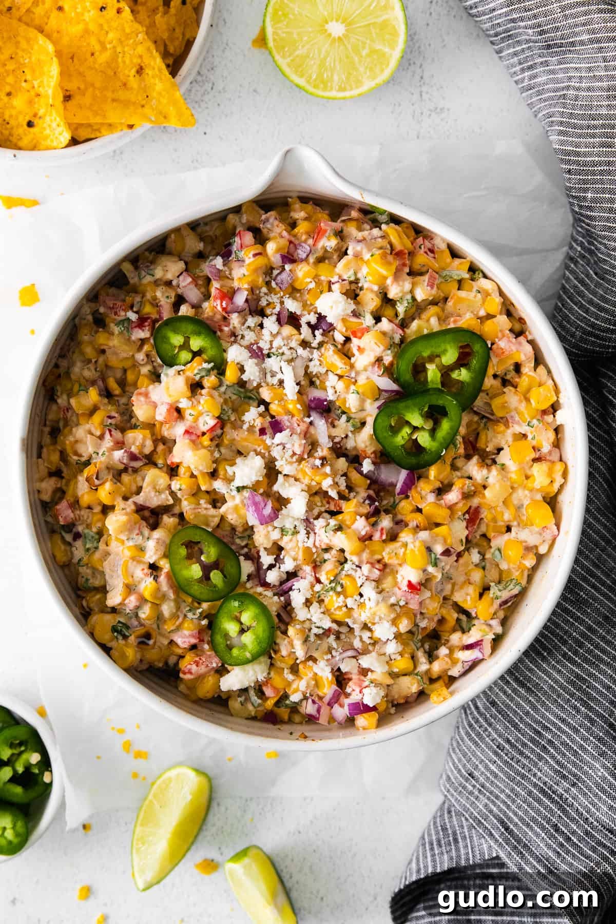 A beautifully presented Mexican corn salad, garnished with a sprig of fresh jalapeño and cilantro.