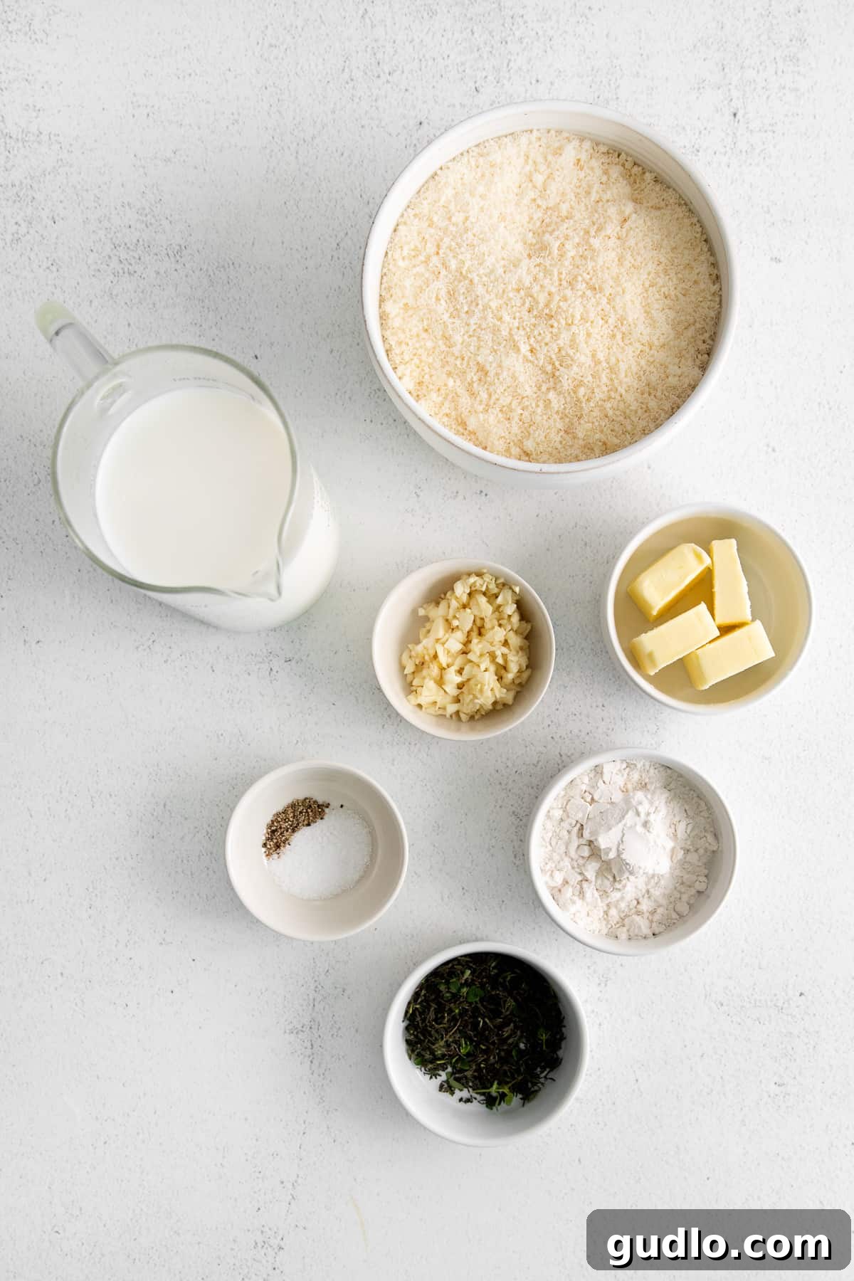 Creamy Garlic Parmesan Sauce 3 Various small bowls containing fresh garlic, grated Parmesan, butter, and other ingredients, laid out for making garlic parmesan sauce.