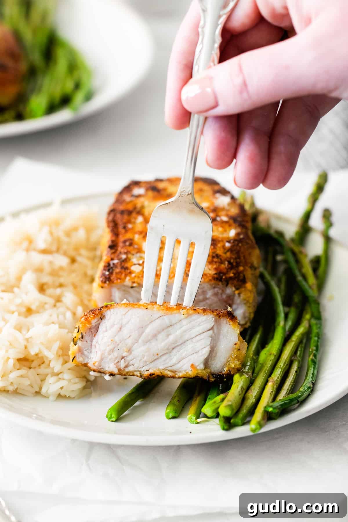 Golden Parmesan Pork Chops 2 A fork holding a piece of parmesan crusted pork, showcasing its crispy crust.