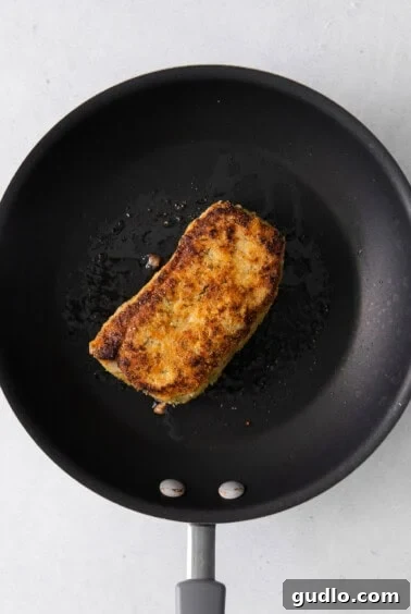 Golden Parmesan Pork Chops 13 A pork chop cooking in a skillet.