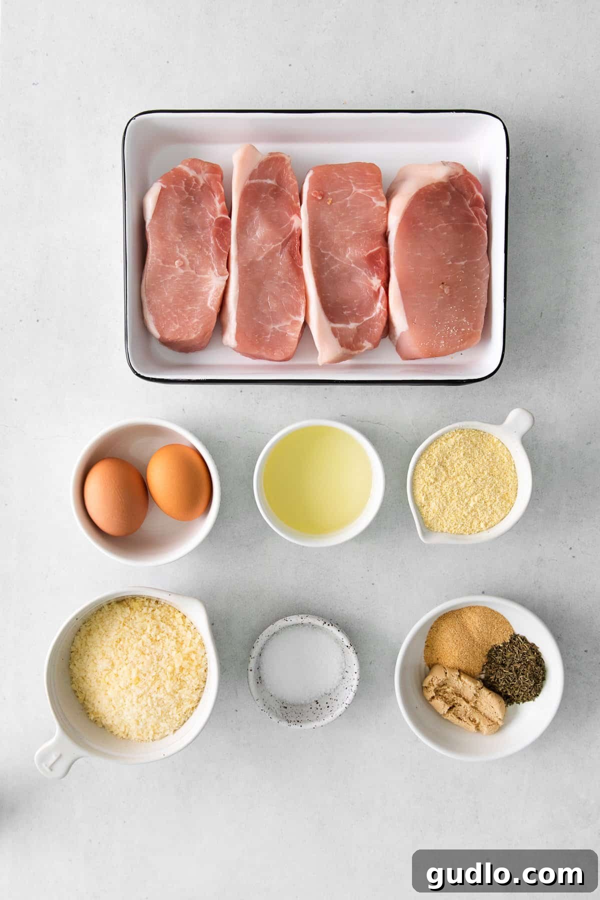 Golden Parmesan Pork Chops 3 Ingredients laid out for making parmesan pork chops, including pork, eggs, and parmesan cheese.