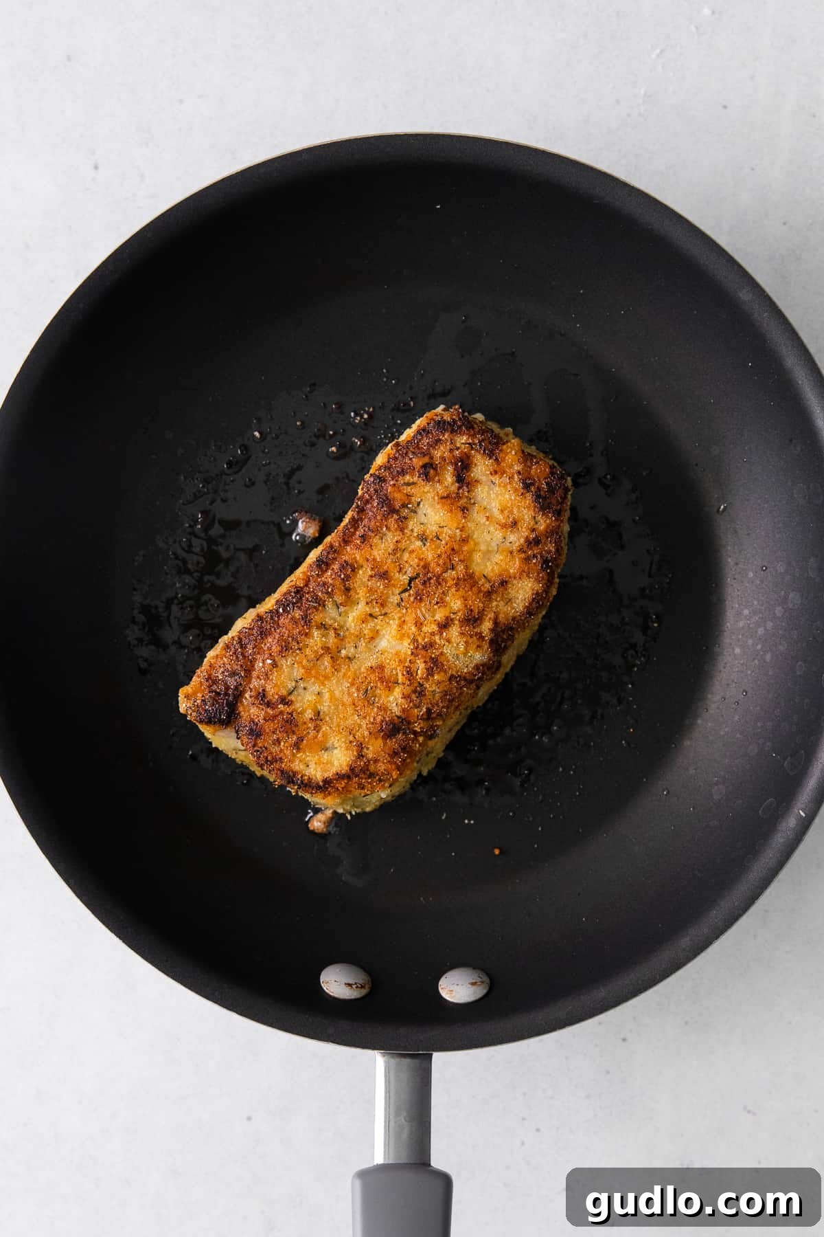 Golden Parmesan Pork Chops 7 A parmesan crusted pork chop sizzling in a cast iron skillet.