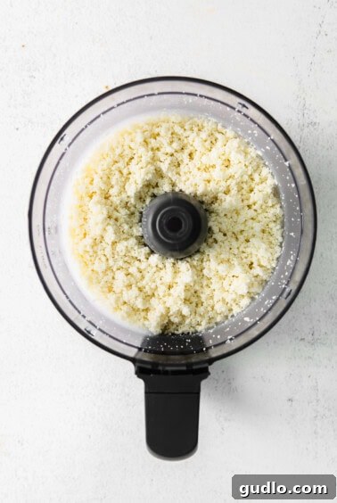 A food processor filled with crumbled white queso fresco cheese.