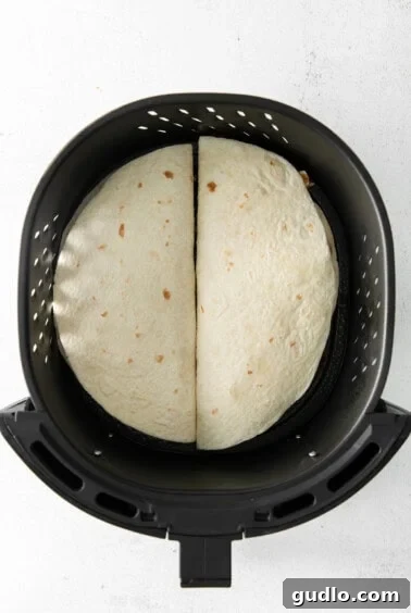 Quick and Crispy Air Fryer Quesadillas 6 Two quesadillas cooking in an air fryer basket.