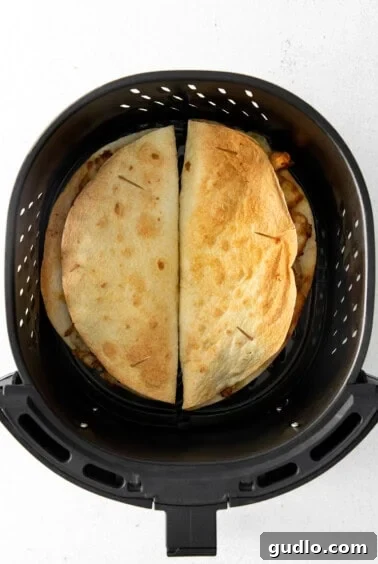 Quick and Crispy Air Fryer Quesadillas 7 An air fryer with two cooked quesadillas inside.