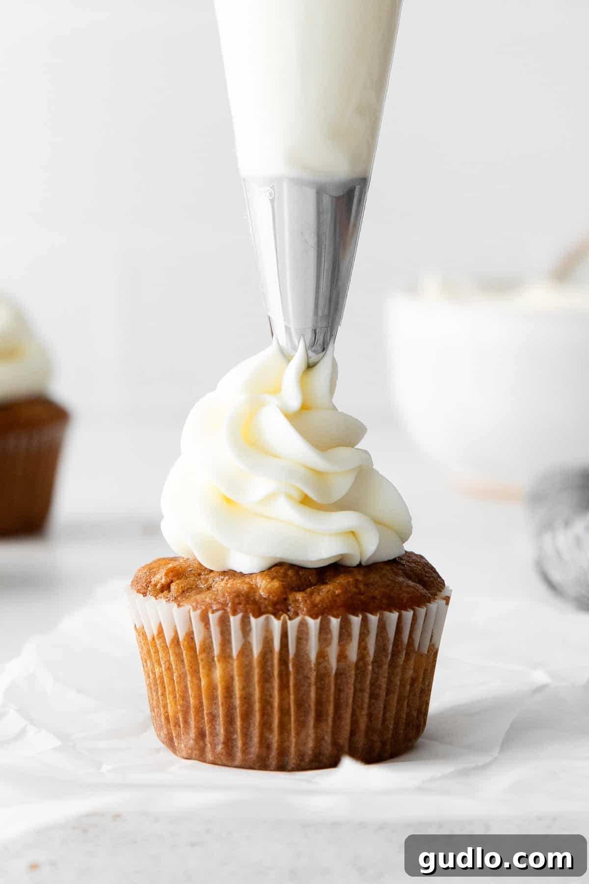 Velvety Vanilla Cream Cheese Frosting 2 Piping fluffy vanilla cream cheese frosting onto a cupcake, ready to be enjoyed.