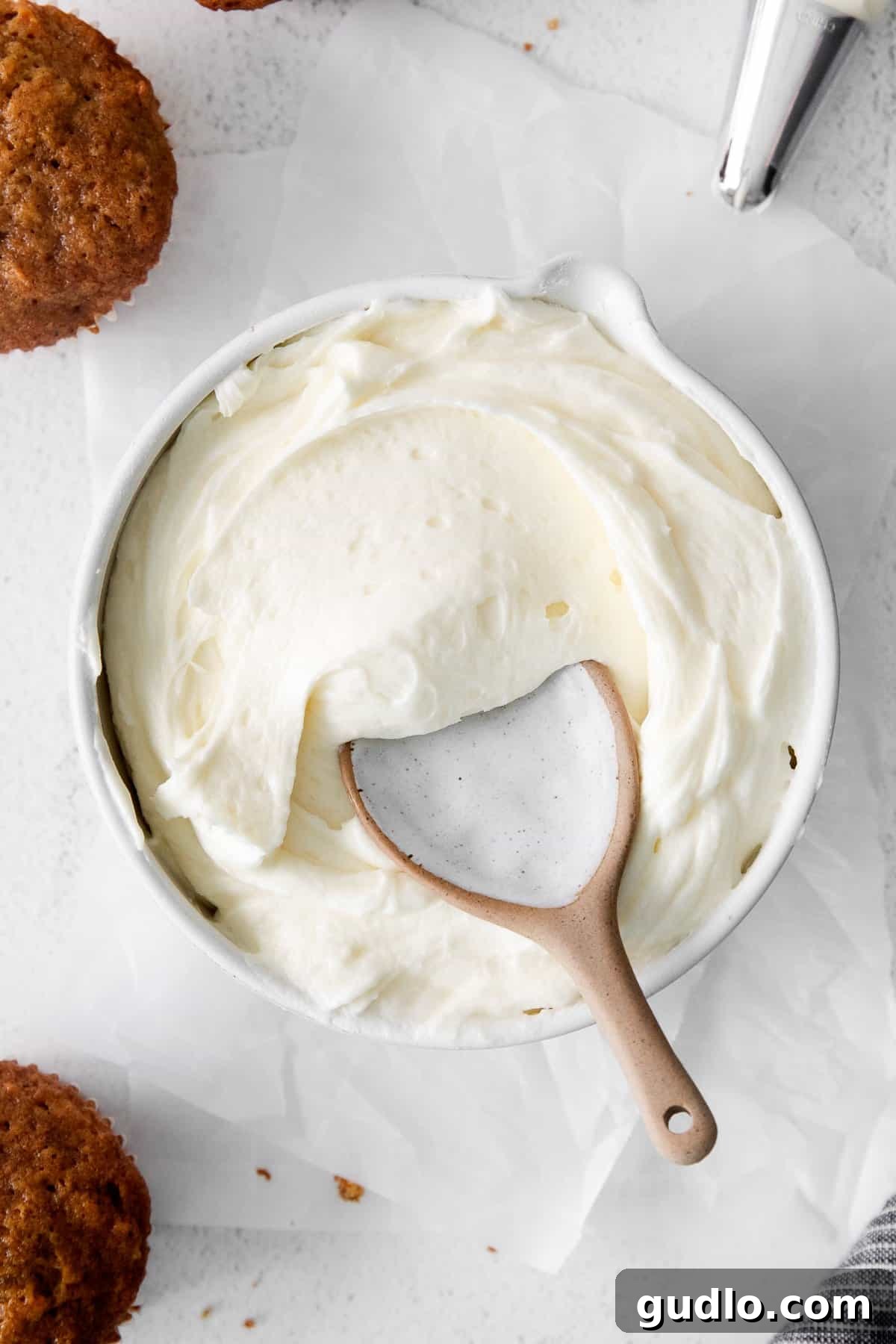 Velvety Vanilla Cream Cheese Frosting 6 A bowl of vanilla cream cheese frosting with a spoon, showing its creamy texture, ready to be used or stored.