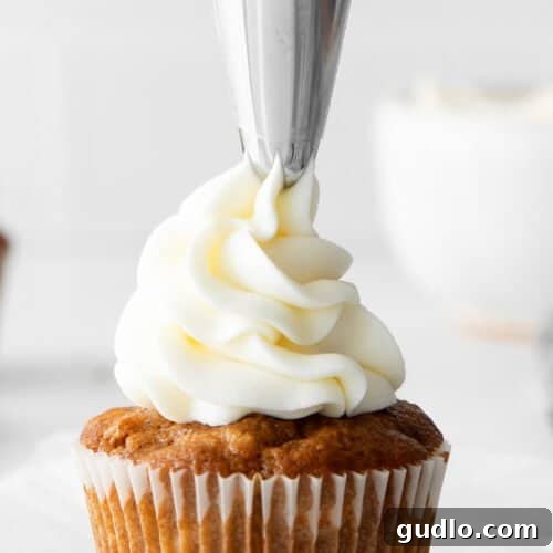 Frosting a cupcake with cream cheese frosting.
