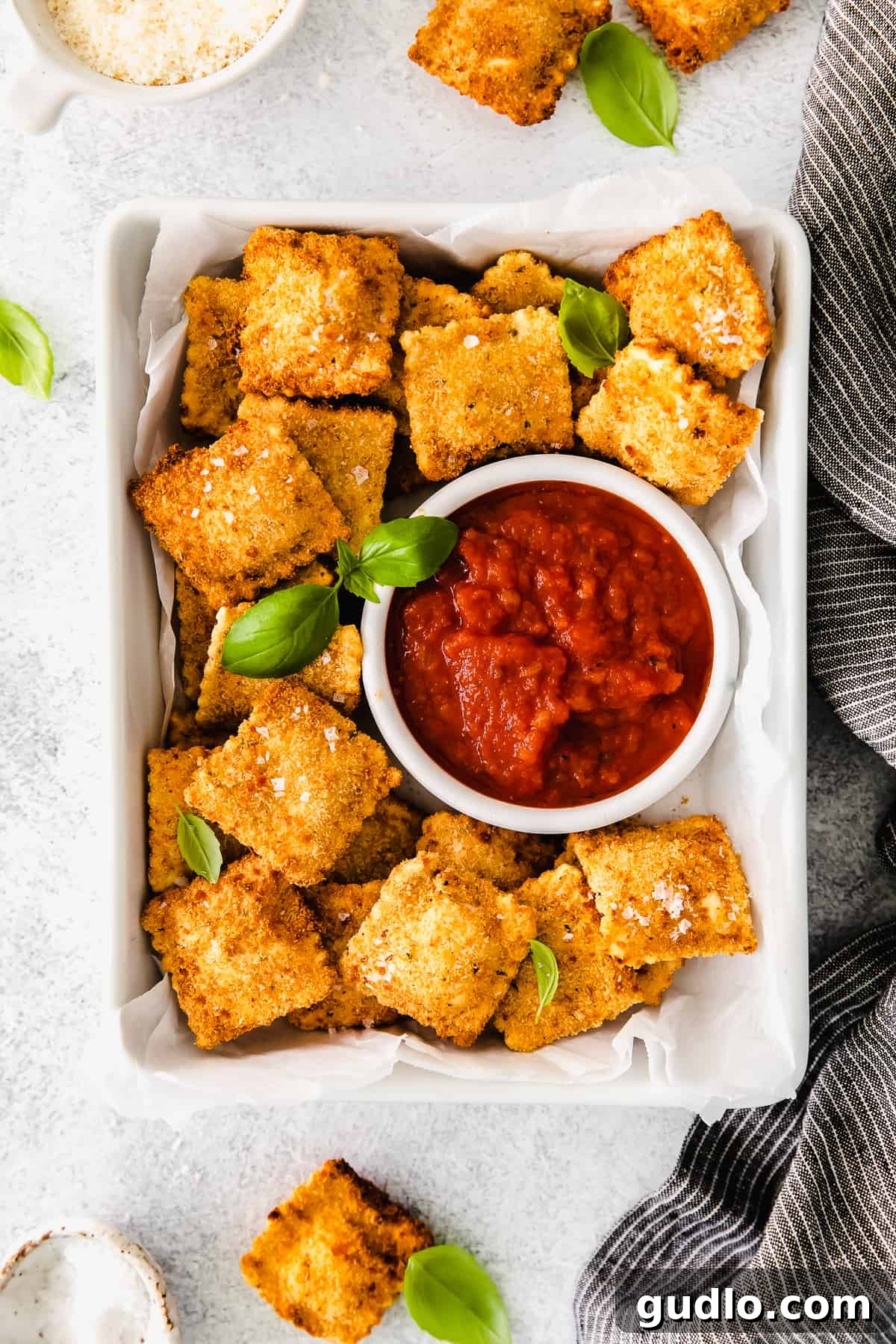 Perfectly golden brown and crispy air fryer ravioli, artfully arranged on a plate next to a small bowl of rich, vibrant marinara sauce, ready for dipping.