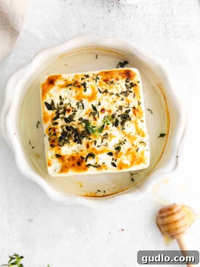 Grilled Feta Cheese Grilled feta cheese in a small ramekin, sizzling and golden brown, garnished with fresh herbs.