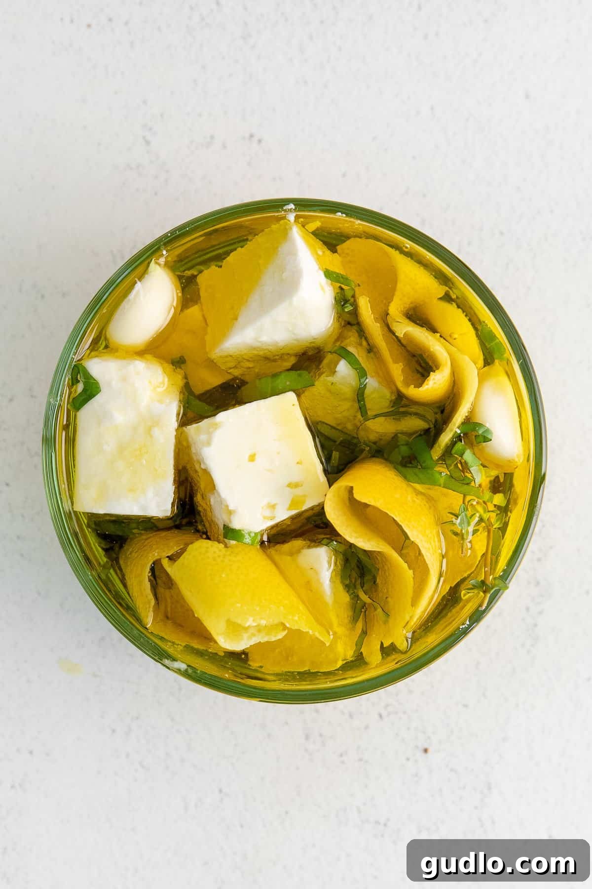 Feta Cheese Unveiled 2 Marinated Feta cheese cubes in a glass jar with herbs and olive oil, ready for snacking or cooking.