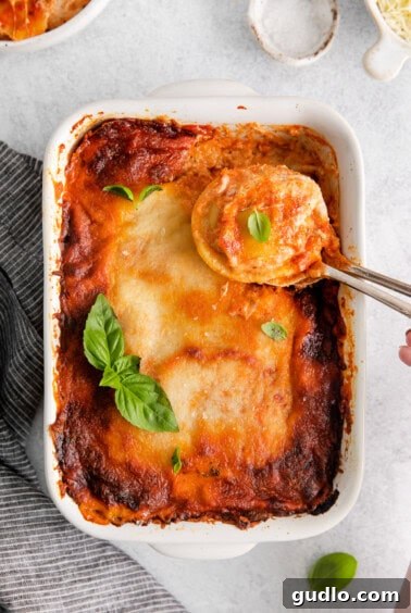 Baked ravioli lasagna in a white dish, resting after being removed from the oven.