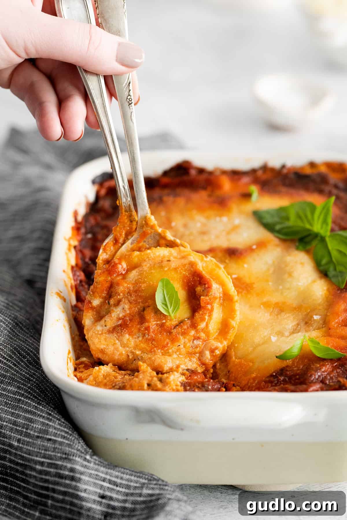A spoonful of hot and cheesy ravioli lasagna being lifted from the casserole dish, showing the delicious layers.