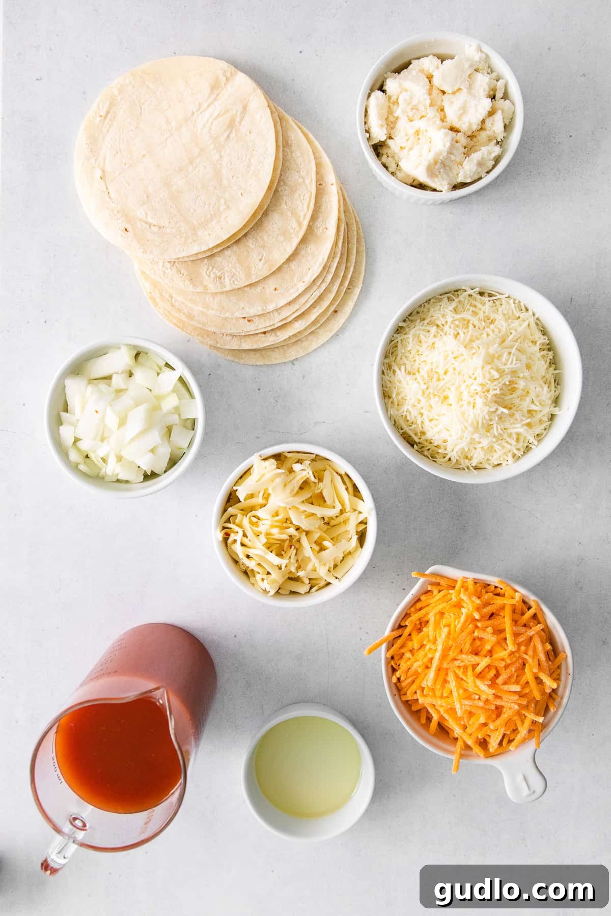 Essential Ingredients for Perfect Cheese Enchiladas Various ingredients for cheese enchiladas laid out in bowls, including tortillas, cheeses, onions, and sauce.